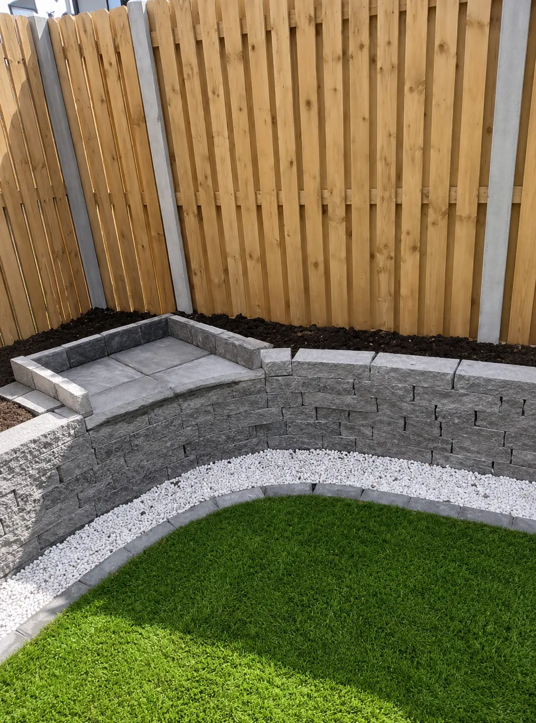 Turf lawn project with stone edging in front of fencing | Farrell Exteriors